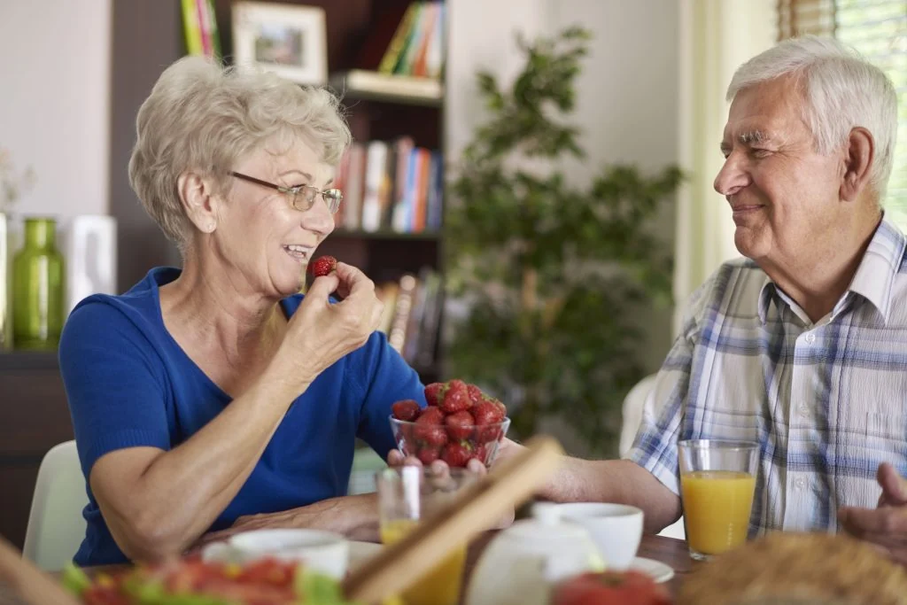 Une femme et un homme partagent des fraises à table.